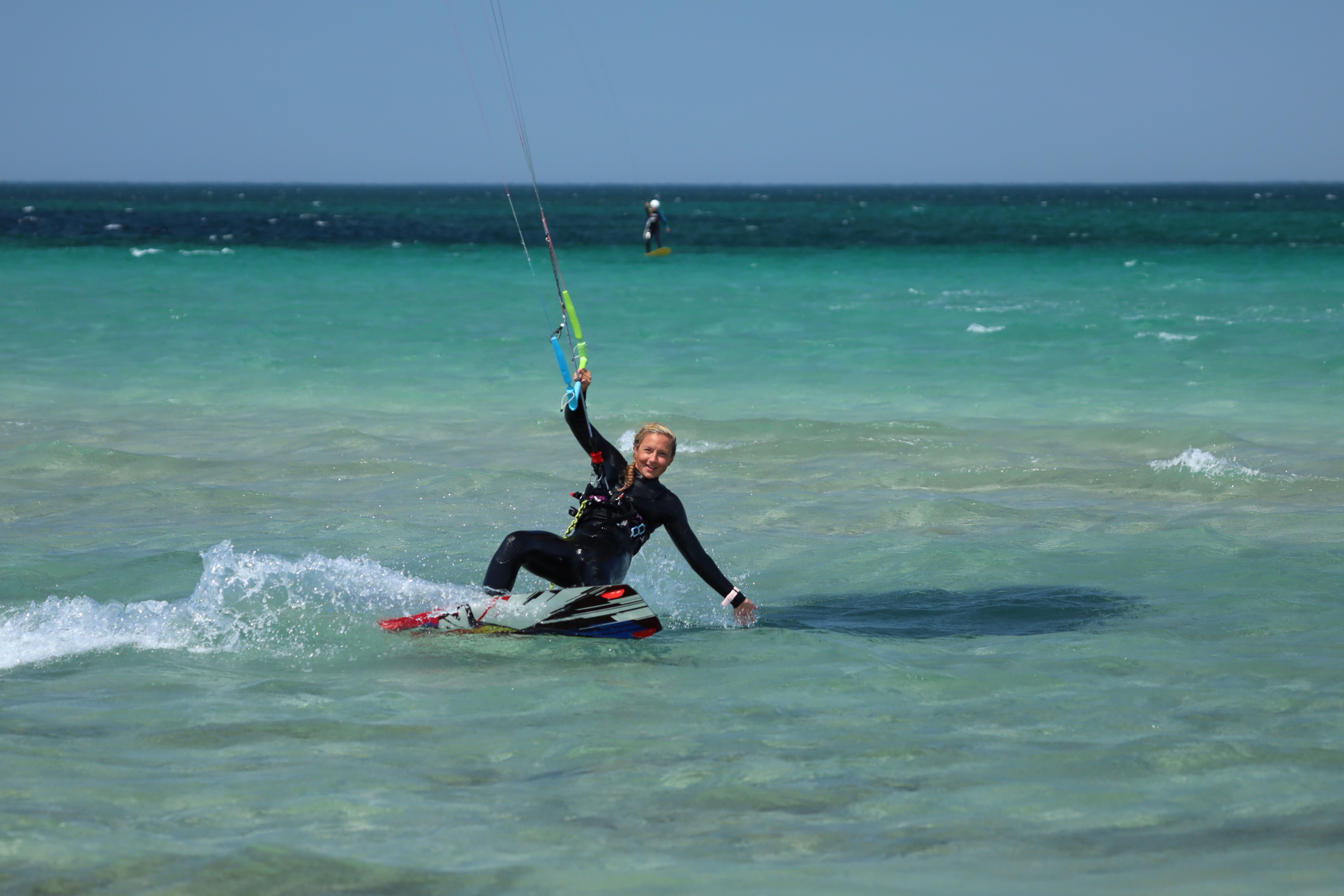 Woman kiteboarding in the sea, enjoying an action-packed water sport on a sunny day.