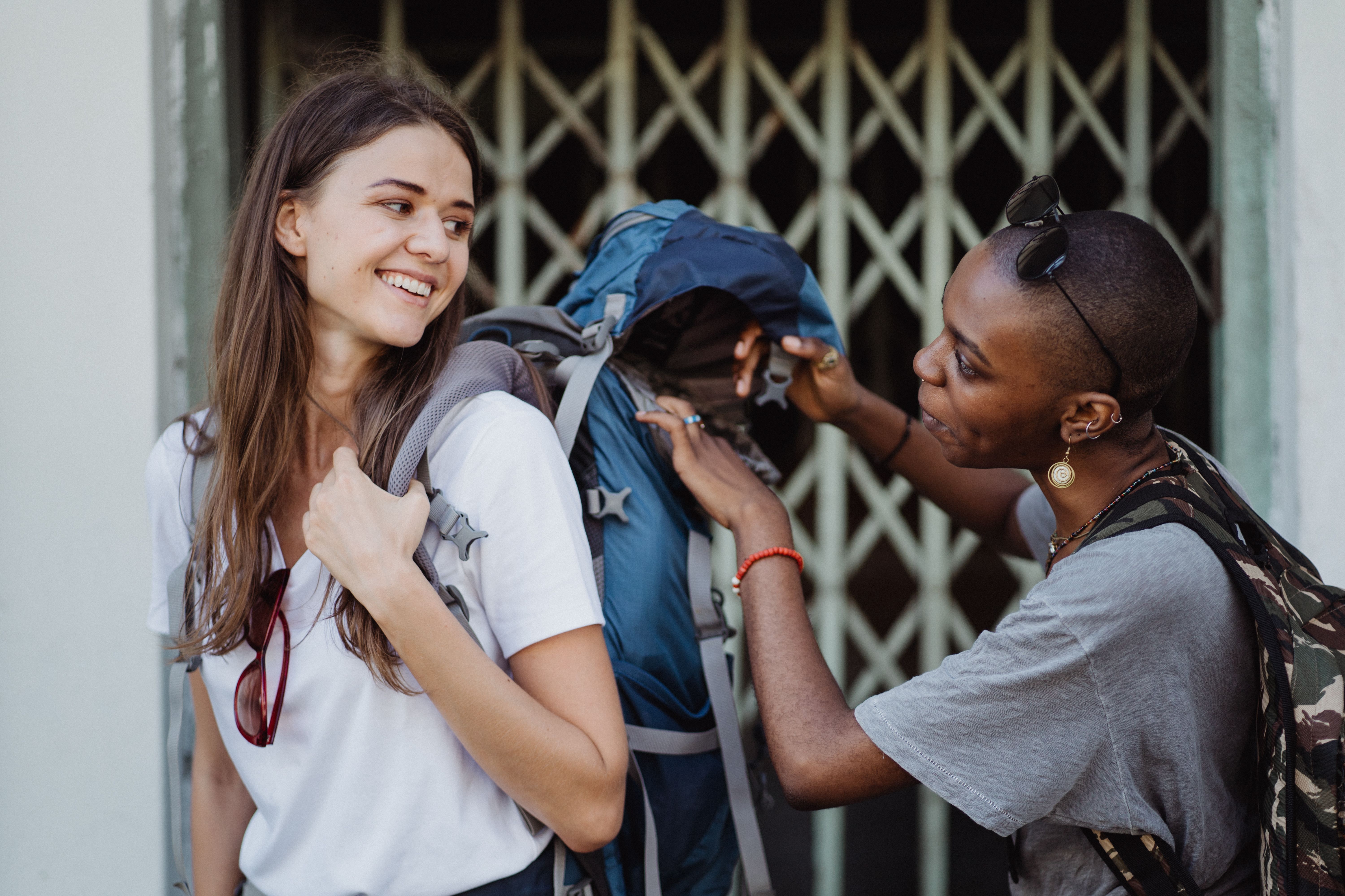 Two young women with backpacks exploring city streets, enjoying their travel and friendship.