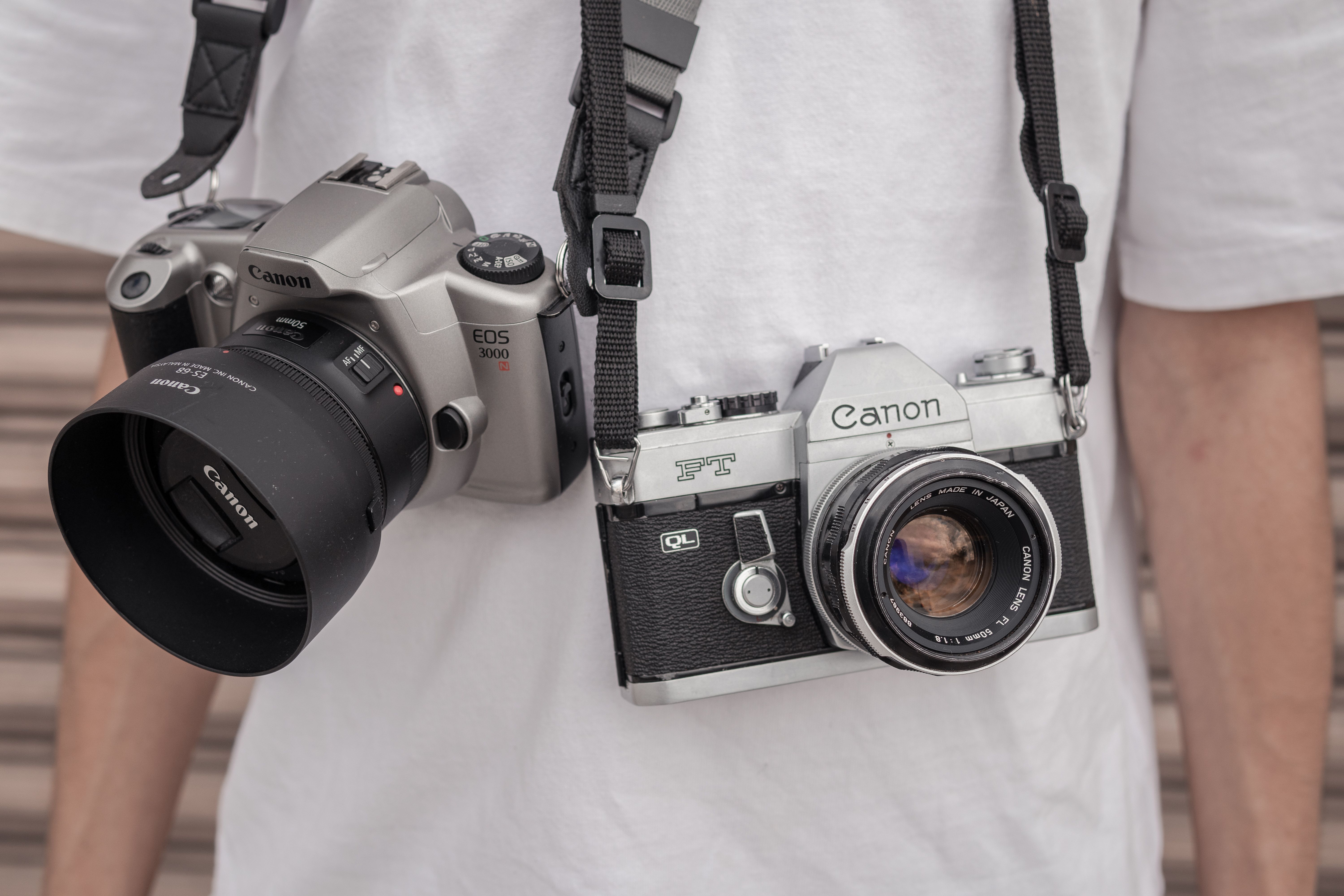 A photographer displays both vintage and modern cameras around their neck.