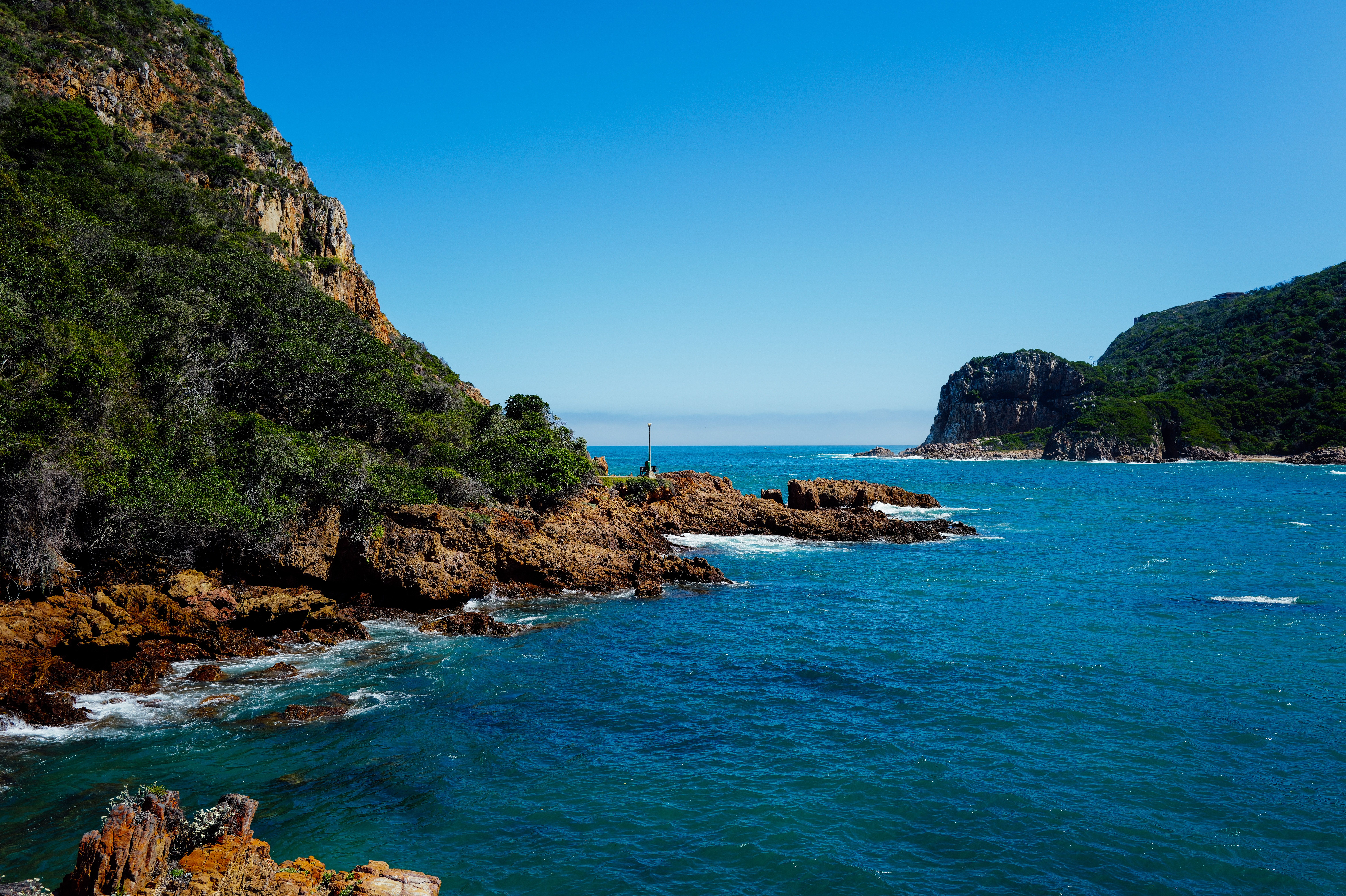 Beautiful coastal landscape at Knysna Heads with clear blue waters and rocky cliffs.