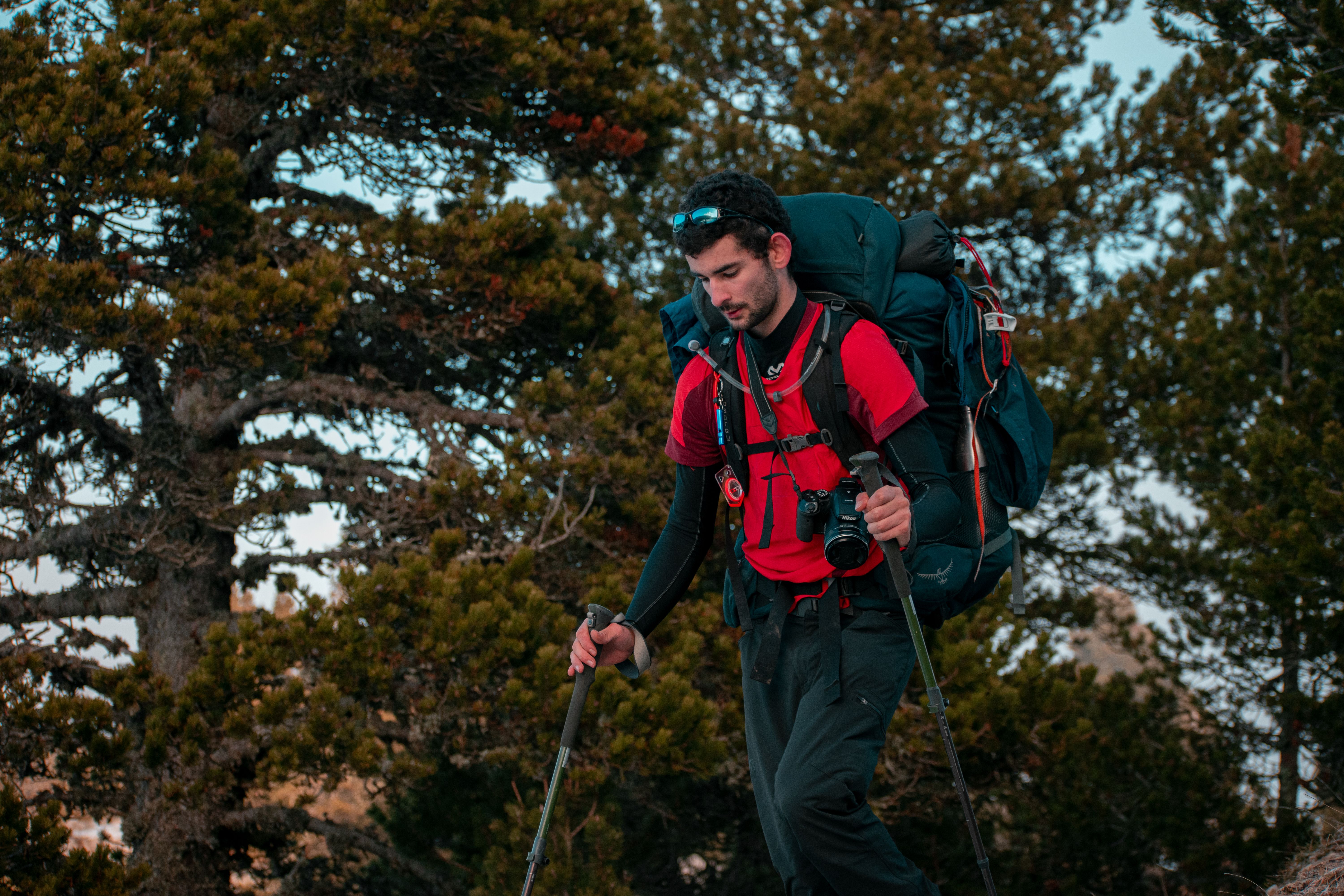 Backpacker hiking through the forest in Chichilianne, France with camera gear and trekking poles.