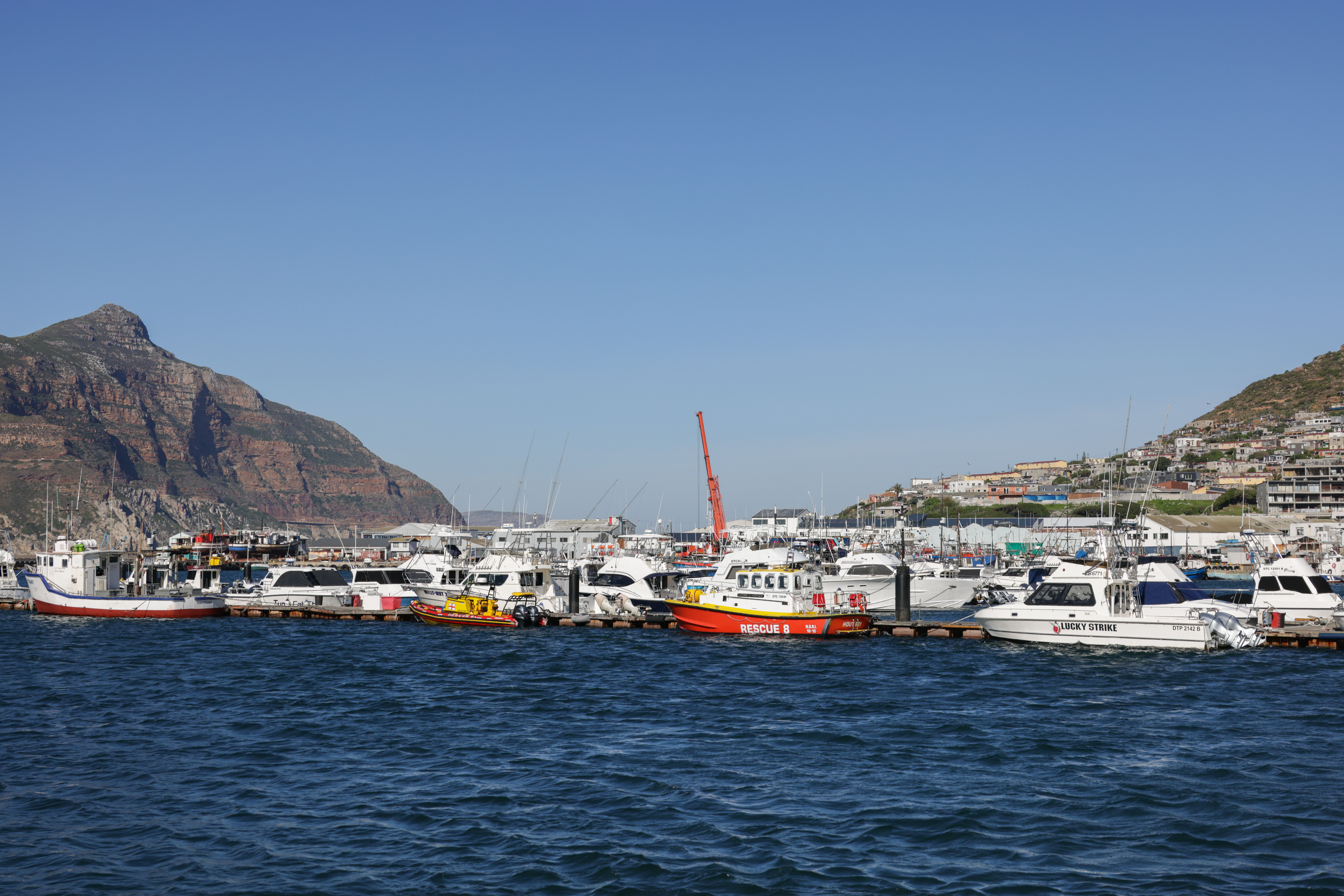 A picturesque view of boats docked at Cape Town harbor with mountains in the background.