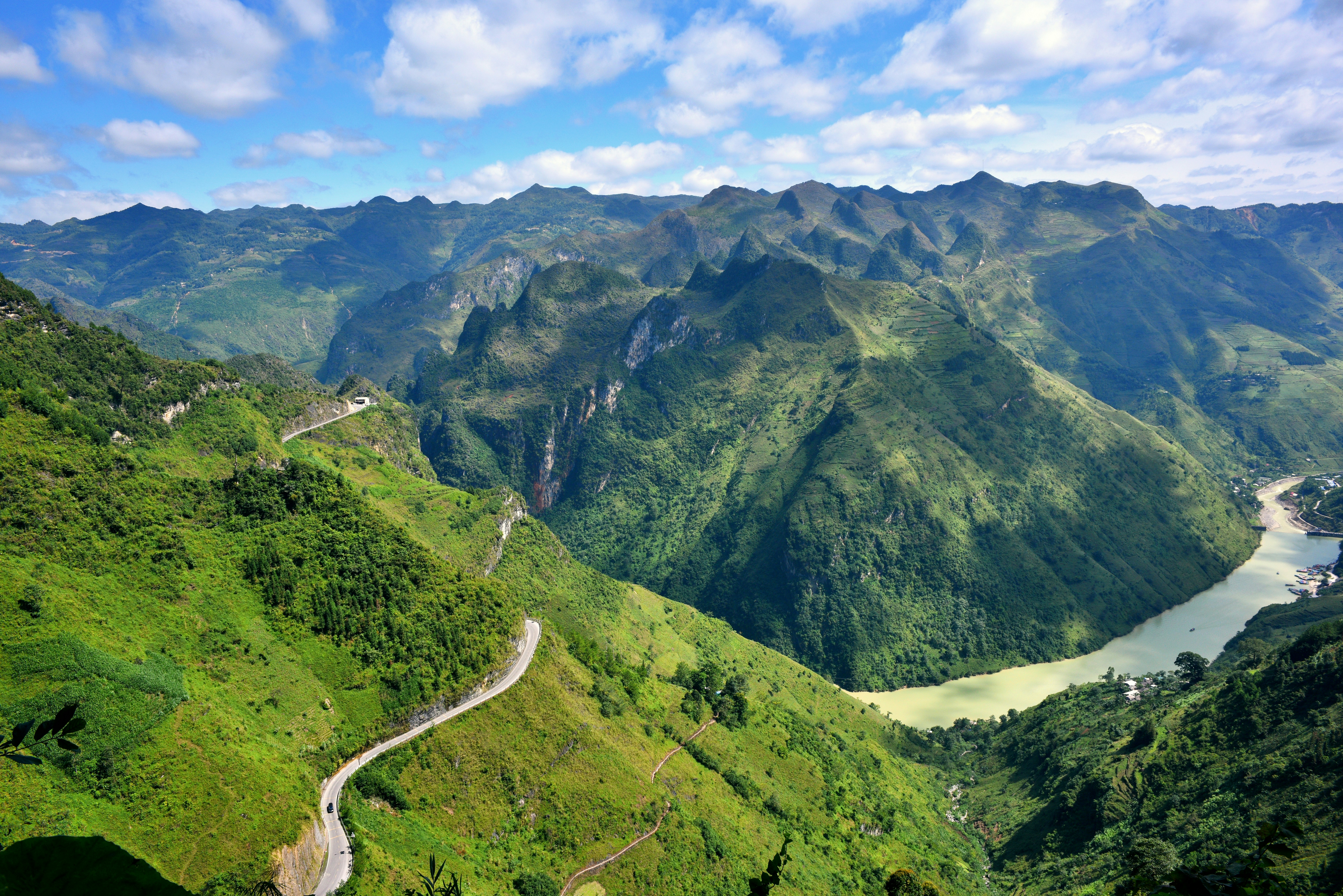 Lush green mountains with a winding river and road.
