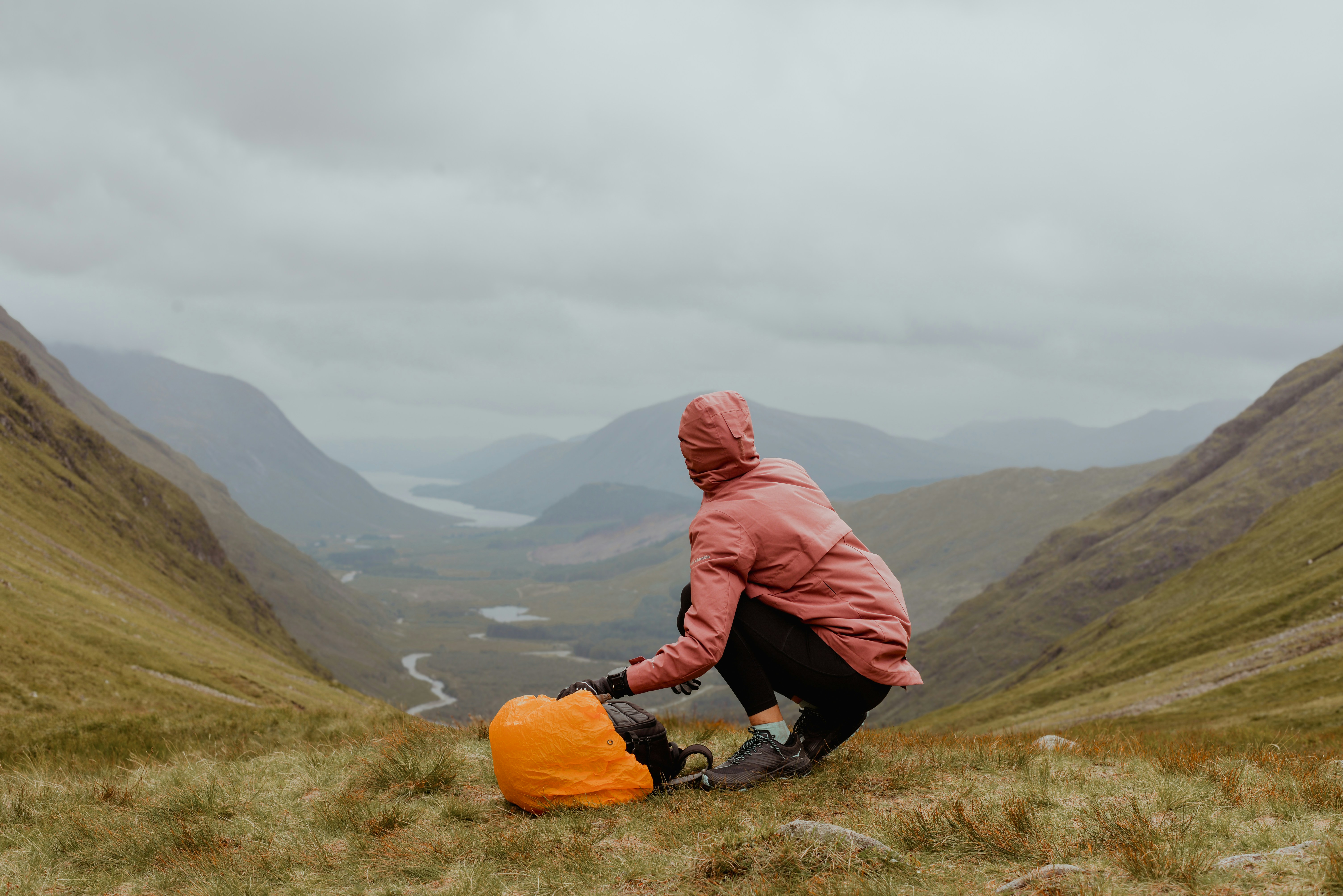 A person in a pink jacket kneeling on a hill