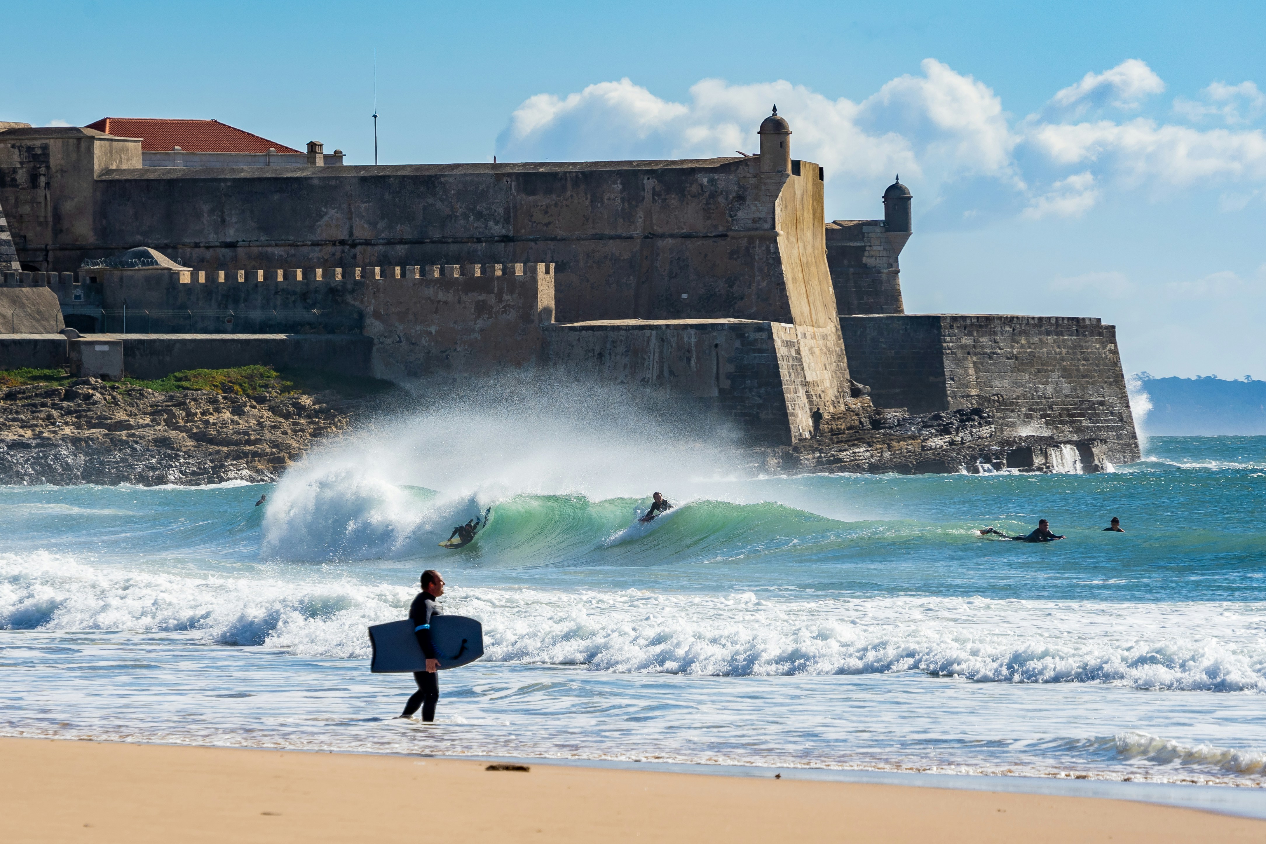 people surfboarding on beach near fort