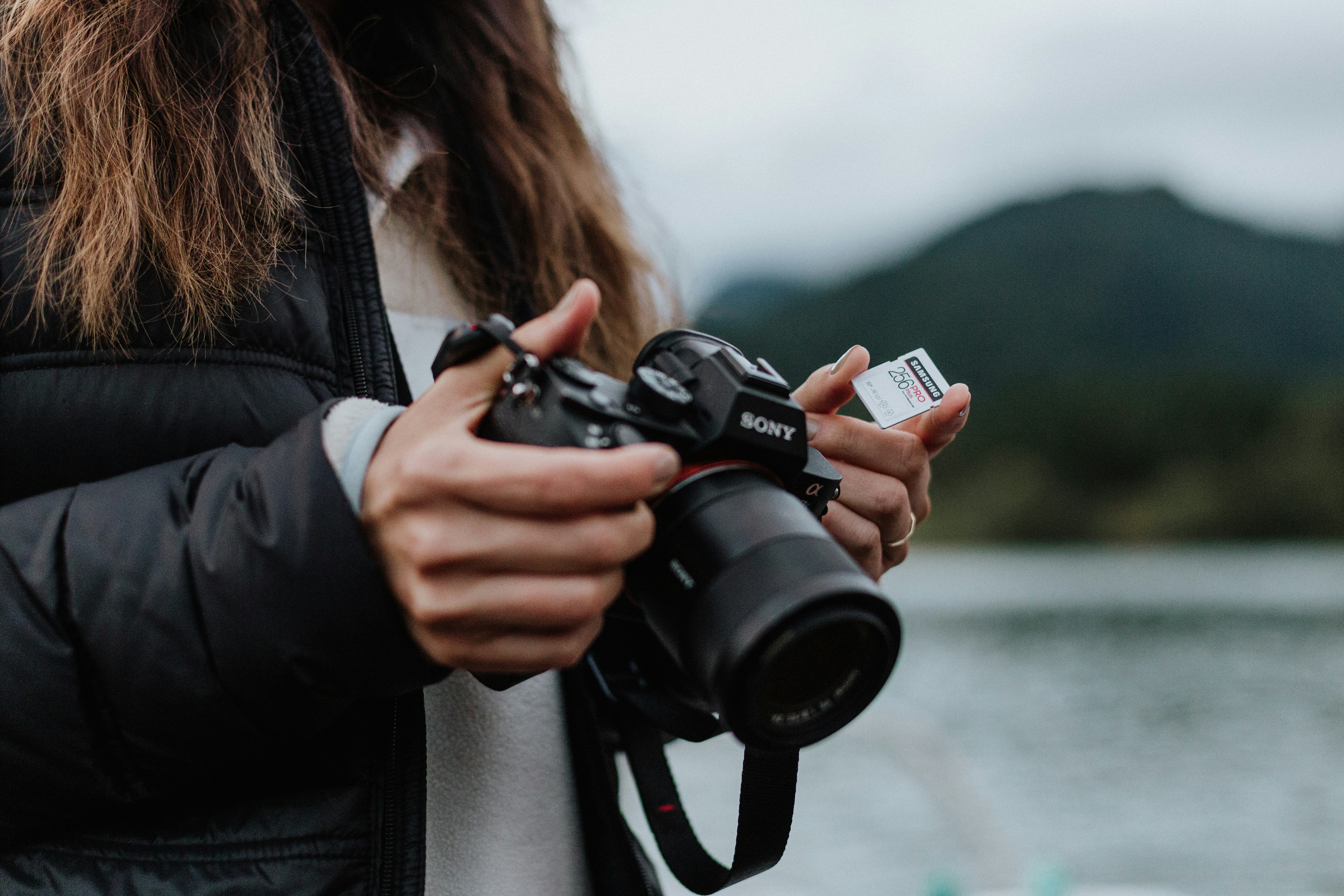 woman in black jacket holding black dslr camera