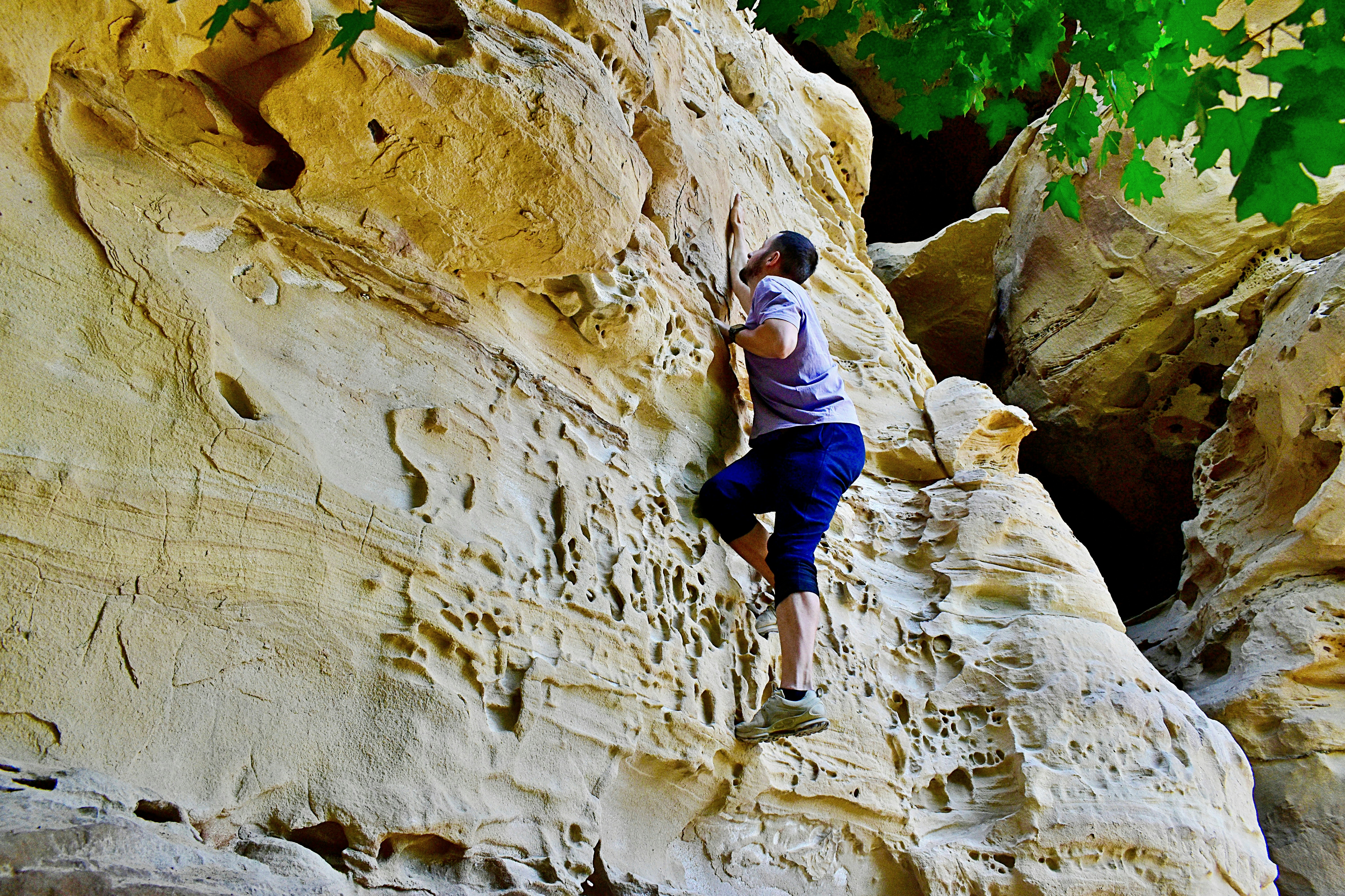 A person rock climbing on a sandy cliff face.